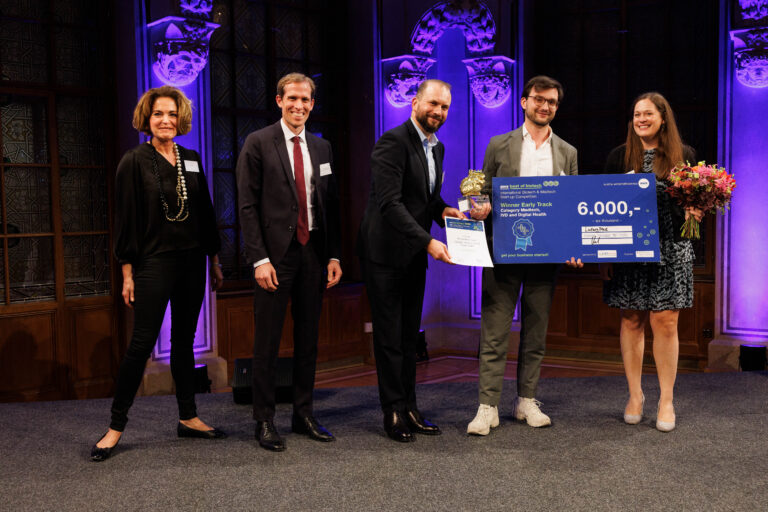 Rafael Boog is standing on stage receiving the winners check for the best of biotech award.